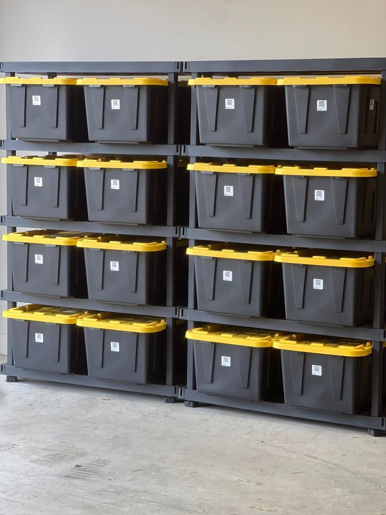 Garage shelving with black and yellow storage totes labeled with Teche QR codes